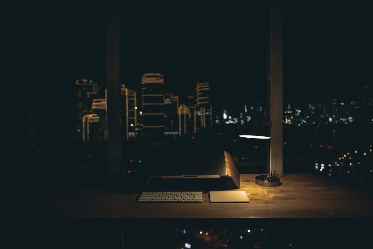 A warm desk lamp casting tungsten light over a late-night study setup