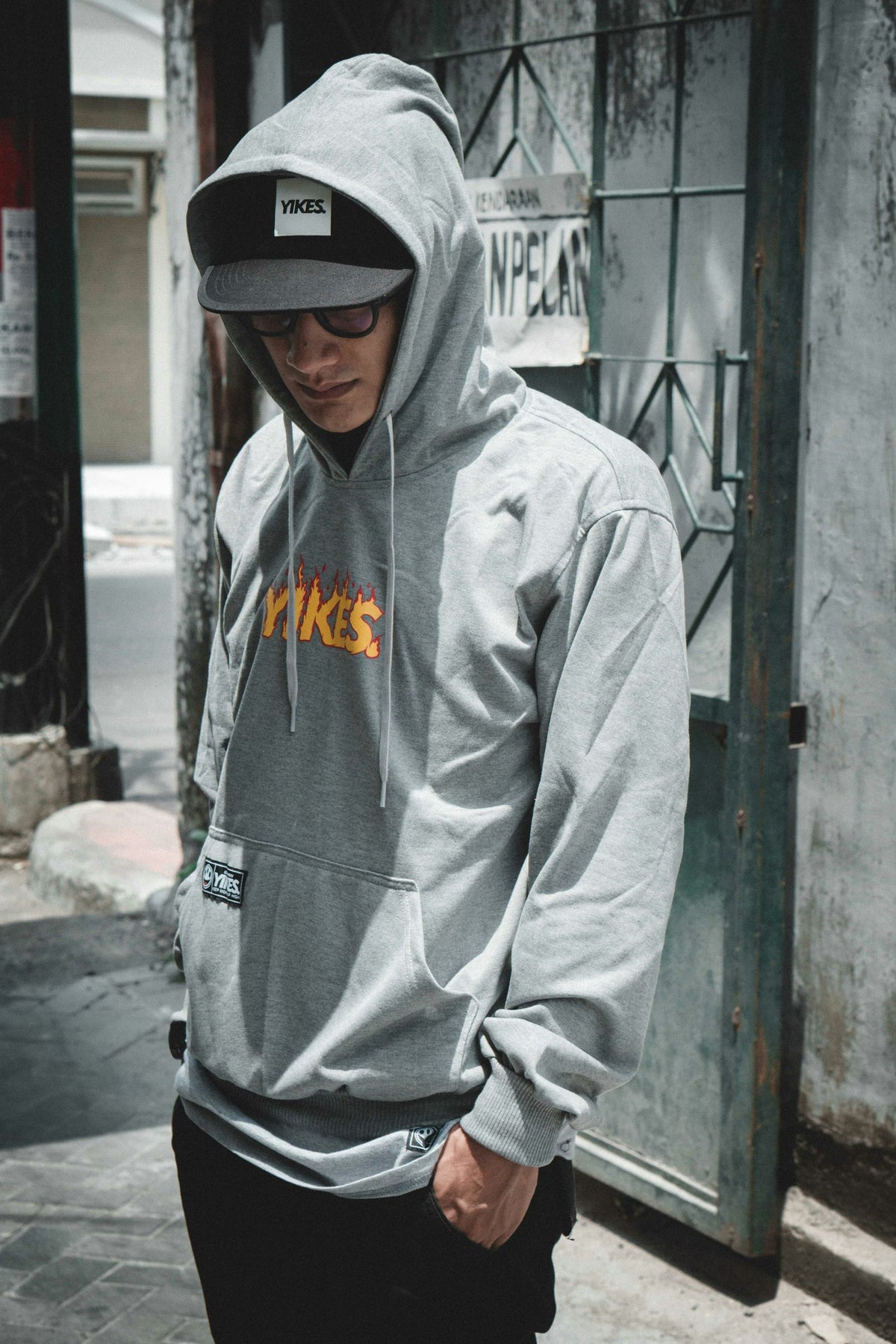 Man in a casual hoodie standing near a wall, effortlessly composed