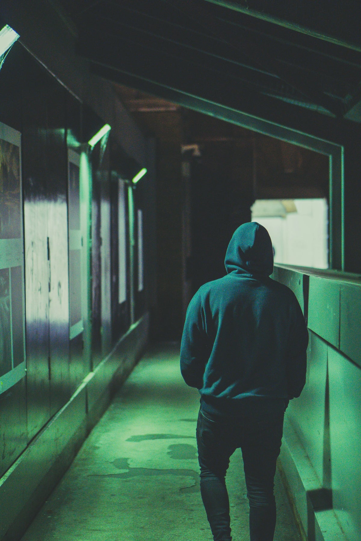 A student walking down a dark London street at night in an oversized hoodie