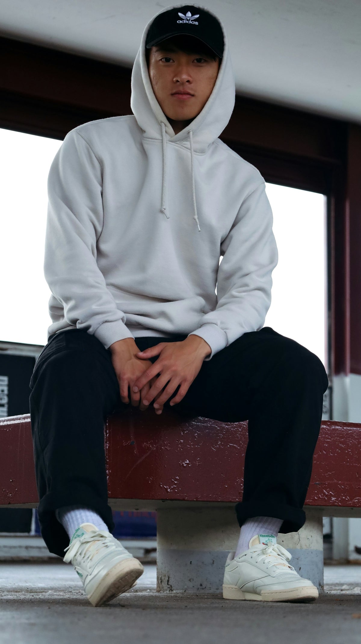 Man in a white hoodie sitting on a sofa, unhurried and at ease