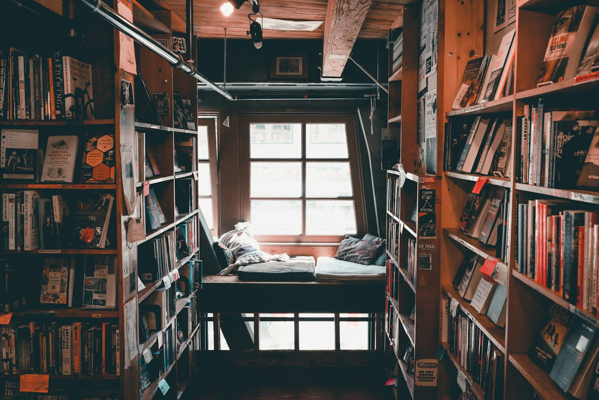 Moody, warmly lit library interior at night with rows of books