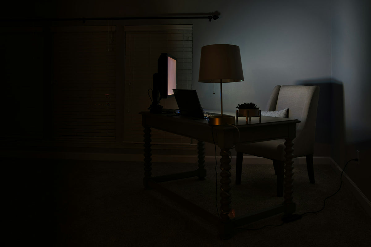 Dark desk lit by a warm tungsten lamp — late night studying