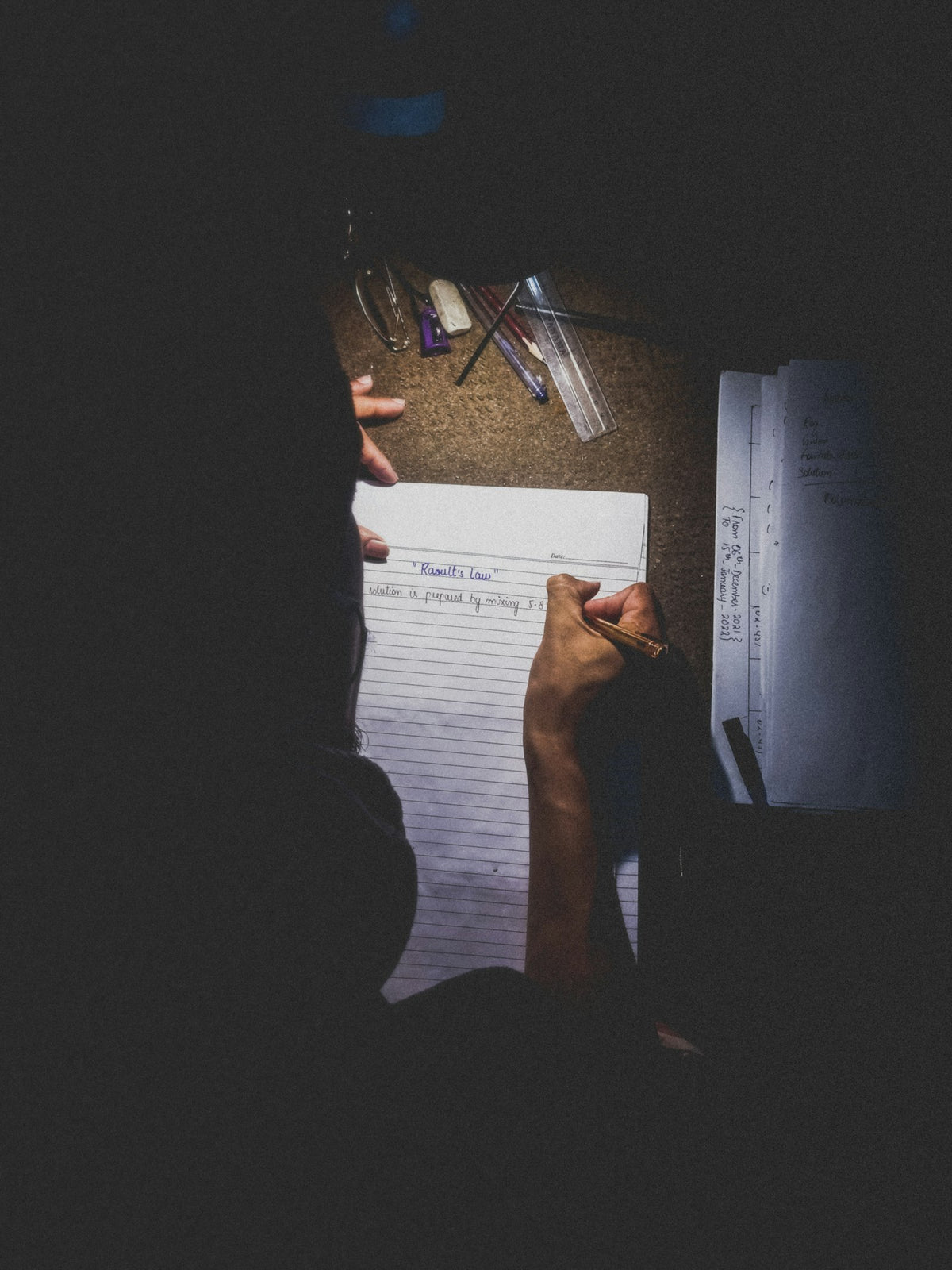Person writing at a desk late at night by lamplight