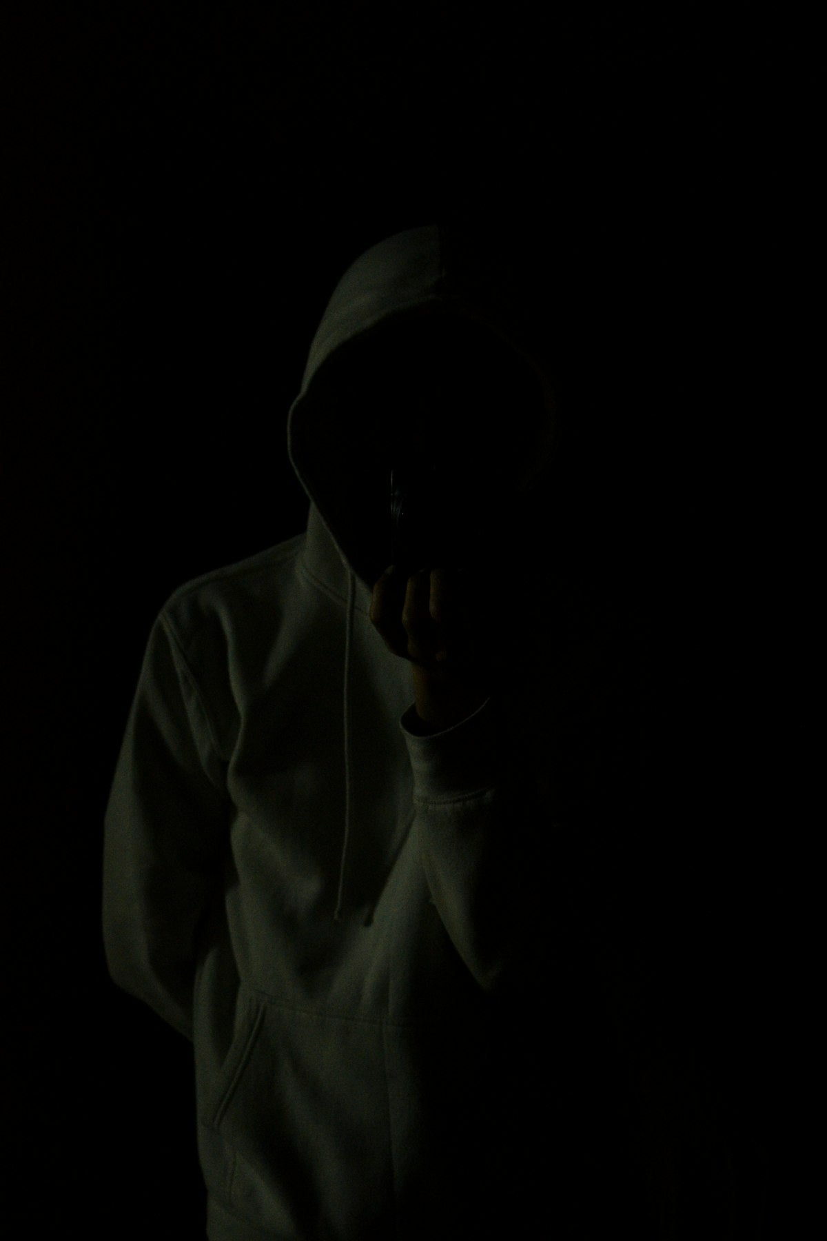 Person wearing an oversized hoodie in dim lighting