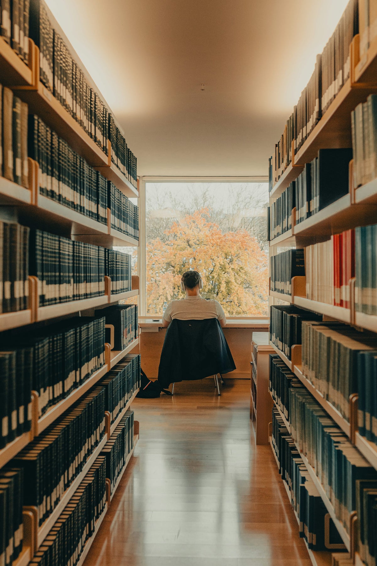 A student studying alone at a library desk in cinematic, low-key light