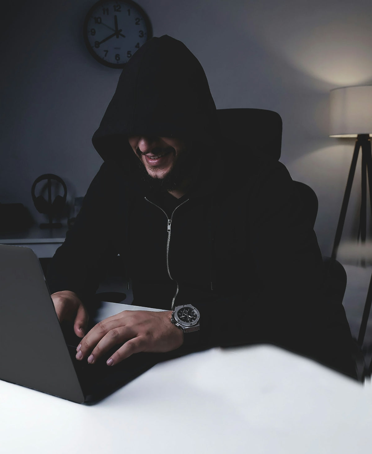Student in an oversized hoodie typing on a laptop late at night
